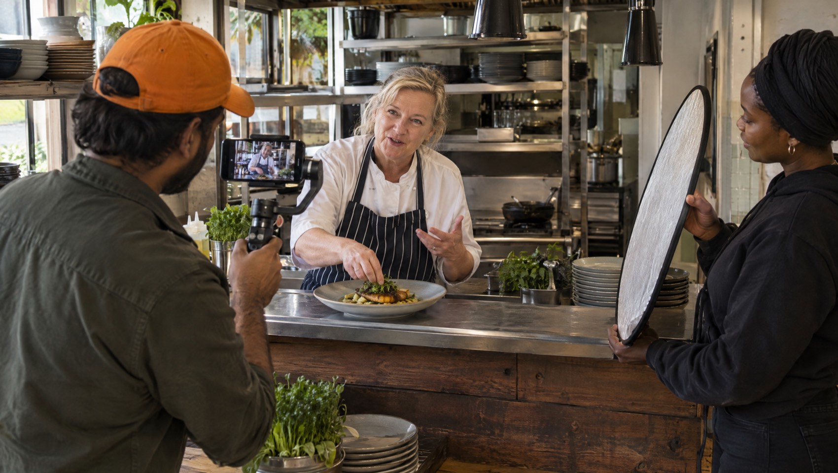 Content crew filming a restaurant owner plating a dish